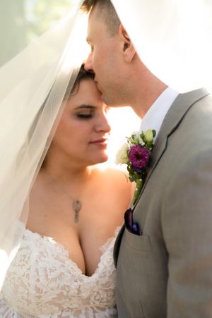 Intimate wedding portrait with evening sunlight highlighting lace dress details.