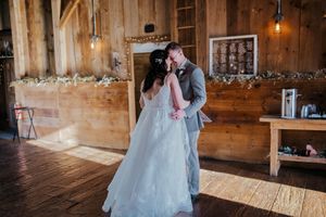 A romantic wedding moment captured in a rustic wooden barn with twinkling lights and decorative elements.