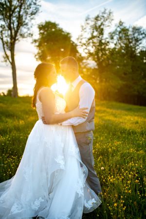 Romantic sunset silhouette of newlyweds embracing in a wildflower meadow.
