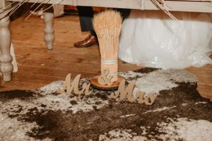 White paint drips onto a wooden floor near a post or table leg.
