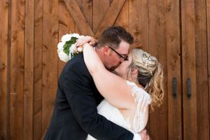 Intimate wedding moment captured against wooden barn doors.