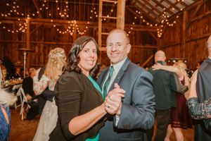 Couples dance in a rustic barn with string lights overhead.