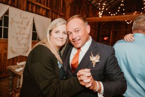 Wedding guests dance at a cozy barn reception with string lights and decor.