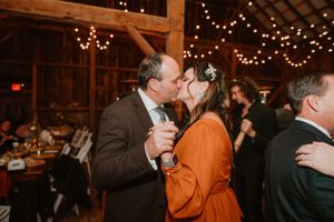 Wedding guests dancing in a barn decorated with string lights overhead.