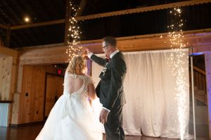 First dance moment under twinkling lights in a rustic barn venue.
