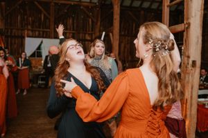 People dancing joyfully at a barn wedding reception.