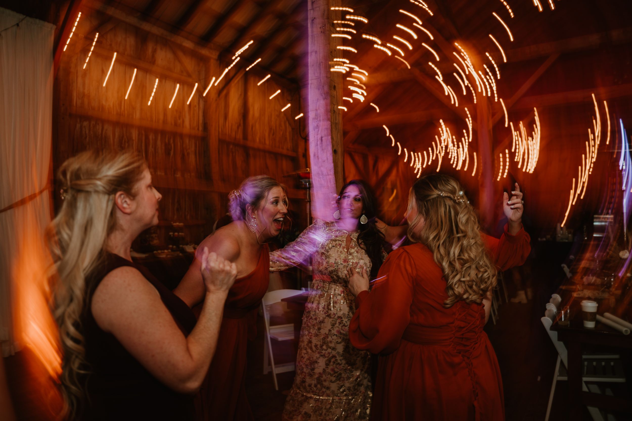 Party guests dancing under warm lighting creating motion blur effects in a rustic venue.