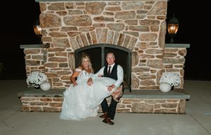 Couple sits together on a stone fireplace patio during evening celebration.