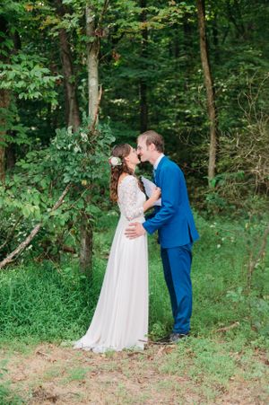 A romantic wedding moment between newlyweds in a forest setting with green foliage.