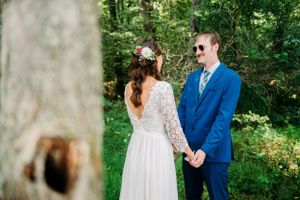 Couple sharing a joyful moment in their wedding attire against a woodland backdrop.