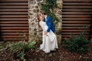 A romantic wedding portrait against a stone and wooden wall with climbing vines.