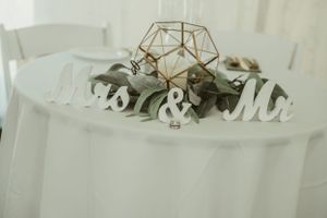 A minimalist wedding table decor with a geometric gold centerpiece and 'Mr & Mrs' sign.