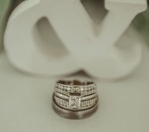 Close-up of diamond wedding rings with intricate band designs against white background.