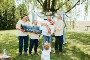 A playful outdoor group photo under a willow tree with light blue decorations.