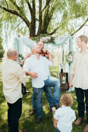 A celebratory moment under a decorated willow tree arch with blue draping.