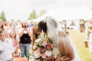 A couple sharing their first kiss at an outdoor wedding ceremony with floral bouquet.