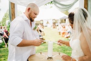 A couple performs a unity candle ceremony during their outdoor wedding.