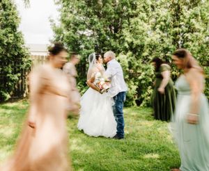 Artistic blurred motion shot of wedding couple surrounded by bridesmaids in pastel dresses.