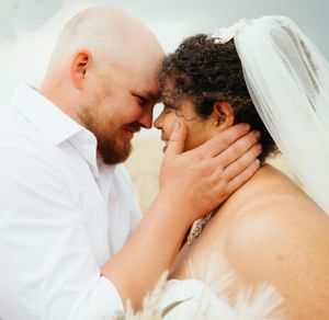 Intimate close-up of newlyweds sharing a tender moment against soft background.