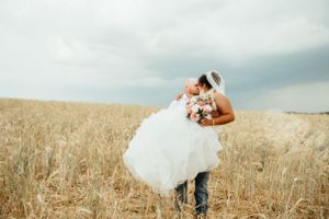 A sweet embrace captured in a golden wheat field during a rustic wedding photoshoot.