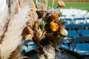 Close-up of dried pampas grass and autumn-colored floral arrangement with orange and brown blooms.