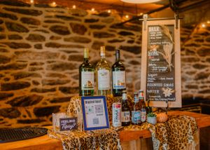 Bar setup with wine bottles and rustic decor against a stone wall with warm lighting.
