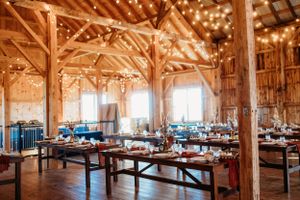 Rustic barn wedding reception venue with string lights and wooden beam architecture.
