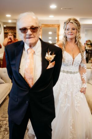 An elegant wedding scene with a bride in a lace gown standing next to a gentleman in a classic navy suit.
