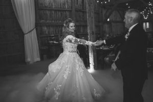 A black and white capture of a romantic first dance in a rustic barn setting.