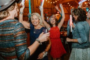 Wedding guests dancing and celebrating on the dance floor of a rustic barn venue.