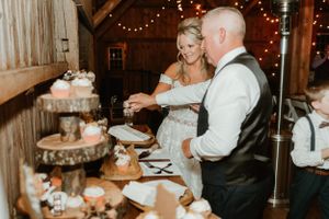 A couple cuts their multi-tiered wedding cake displayed on wooden slices at a rustic reception.