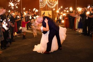 Newlyweds share a romantic kiss during their sparkler exit at night.