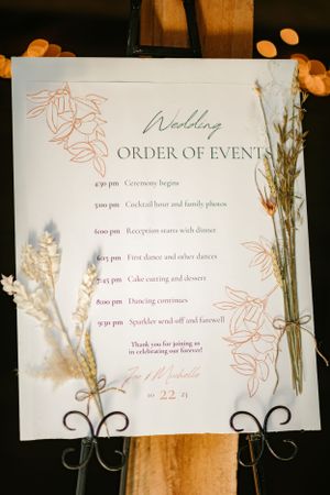 Wedding order of events schedule displayed with elegant floral details and dried flowers.