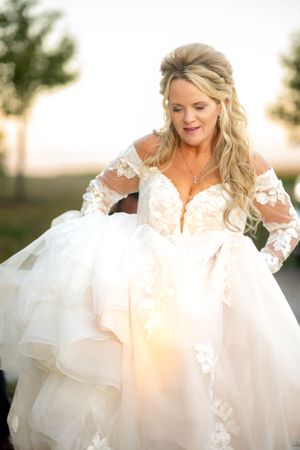 Elegant lace wedding gown with flowing tulle skirt captured at golden hour.