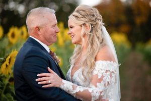 A romantic embrace between newlyweds in front of a blooming sunflower field at sunset.