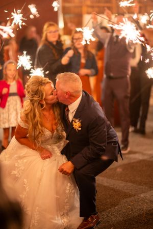 Newlyweds share romantic kiss during sparkler exit at evening wedding reception.