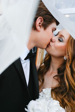 Intimate wedding moment shared under a flowing white veil.