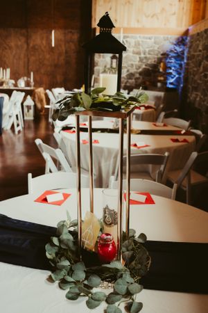 A rustic wedding centerpiece with black lantern and eucalyptus on white tablecloth.