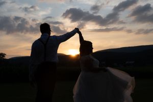 Silhouetted couple dancing at sunset against mountain landscape.