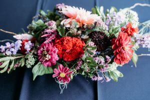 Vibrant floral arrangement with red, pink and purple blooms against dark background.
