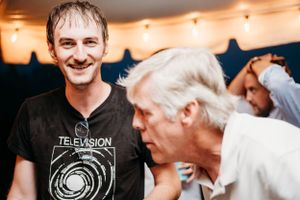Two people share a candid moment at an indoor party with string lights overhead.