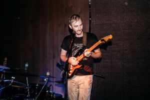 Musician plays orange electric guitar on stage during wedding reception.