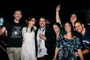 Group celebrates with energetic pose during nighttime wedding reception.