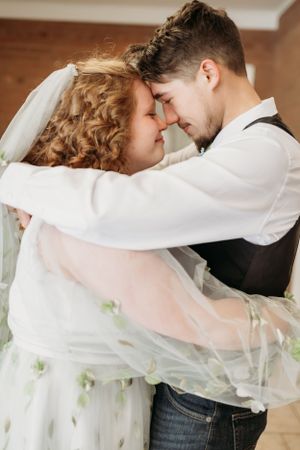 Intimate moment between couple in white dress with green details and formal attire.
