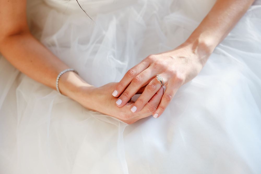 Close up of hands gently folded on white tulle wedding dress fabric.