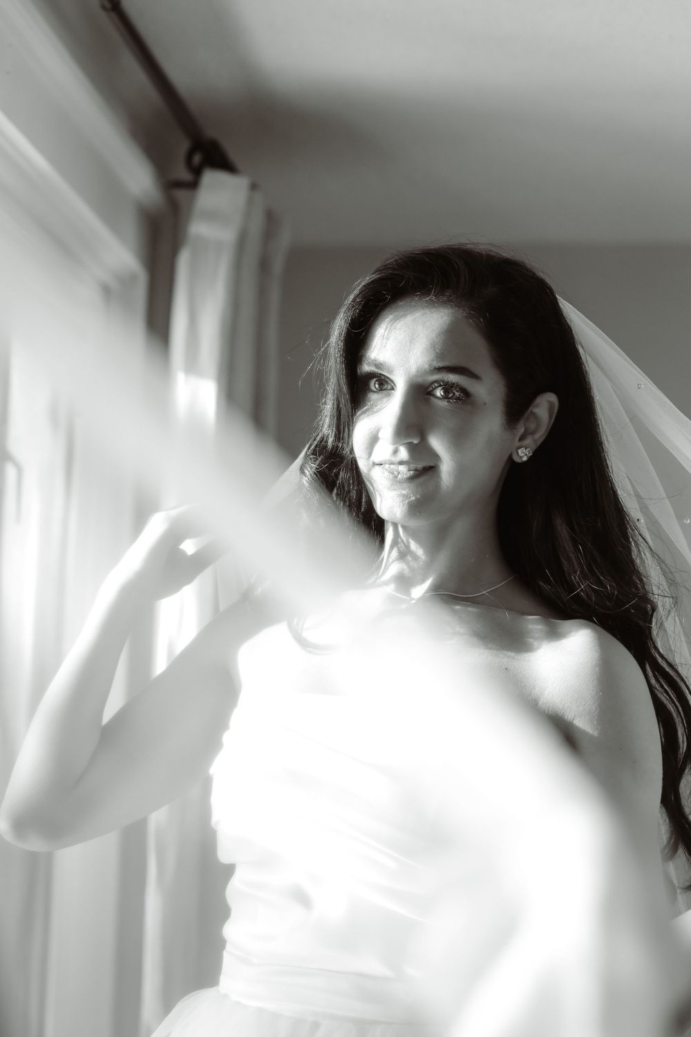 Black and white portrait of bride in strapless gown with soft natural window light.