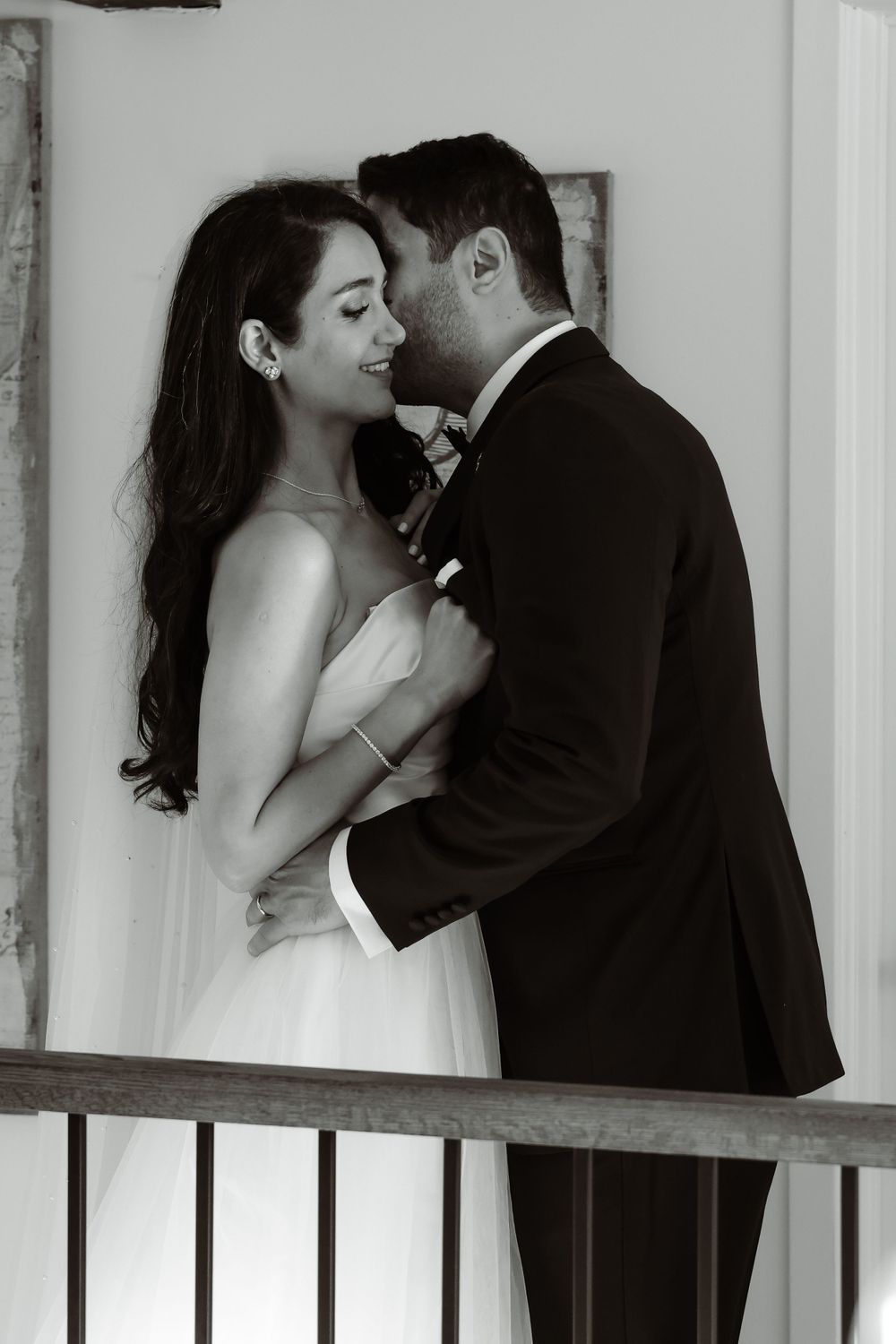 Black and white intimate portrait of newlyweds sharing tender moment on balcony.