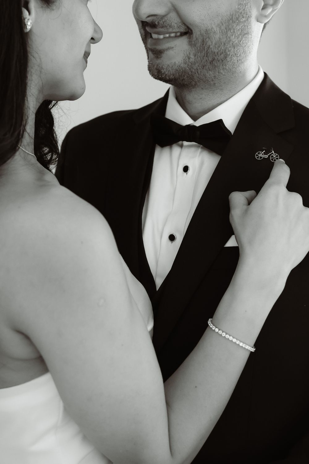 Black and white photo of newlyweds in formal attire with bride's hand gently touching groom's lapel.