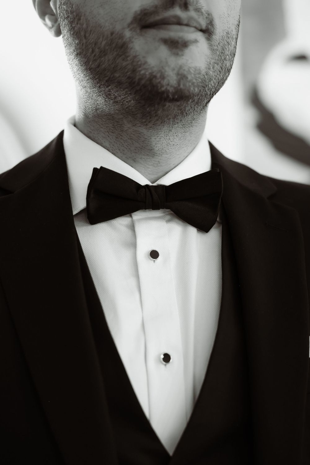 Close-up detail of a formal black bow tie and tuxedo lapel.