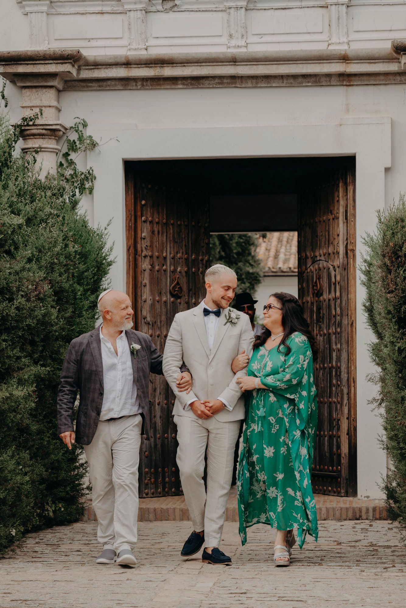 A group walks together wearing coordinated outfits in front of a grand wooden doorway at an elegant venue.